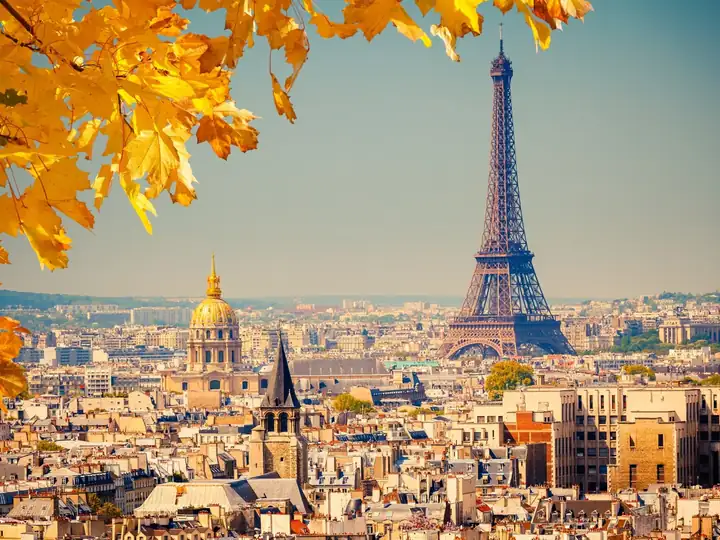 The Eiffel Tower and the rooftops of Paris seen through autumn leaves