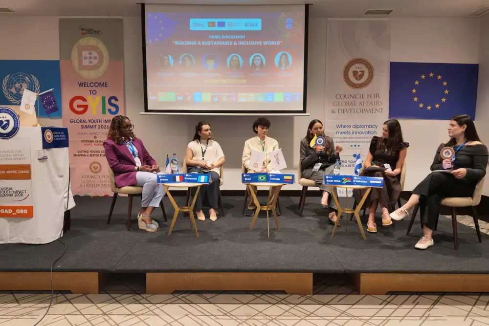 Six delegates seated on a stage for a panel discussion under GYIS and CGAD banners