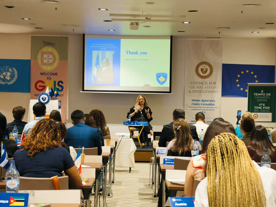 Delegates seated at desks facing a speaker at the front of a conference room hung with UN, EU and summit banners